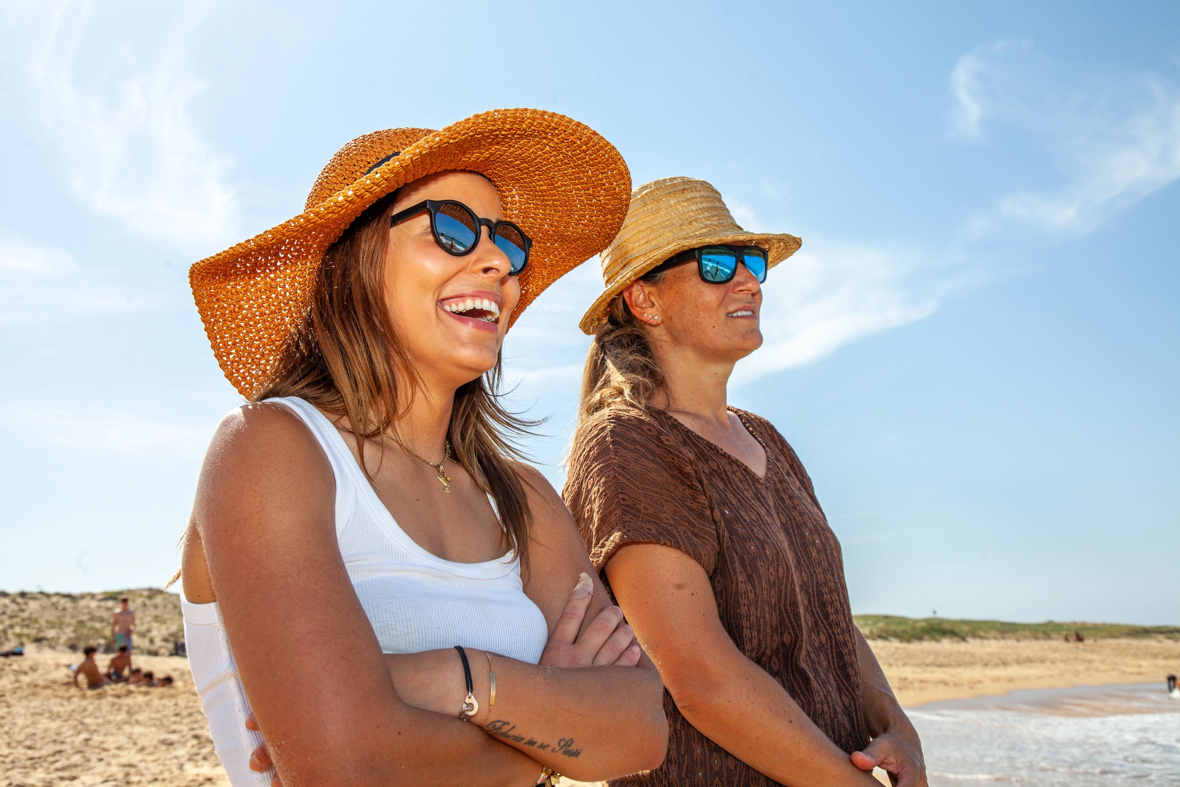 Portrait rapproché de deux femmes souriantes à la plage, portant les lunettes de soleil 2ndlife